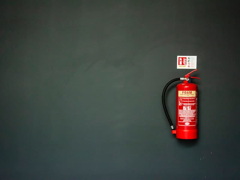 Red fire extinguisher mounted on a commercial building wall